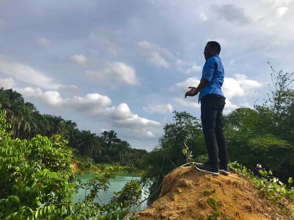 Anietie Usen climbs a hill to have a better view of the green river
