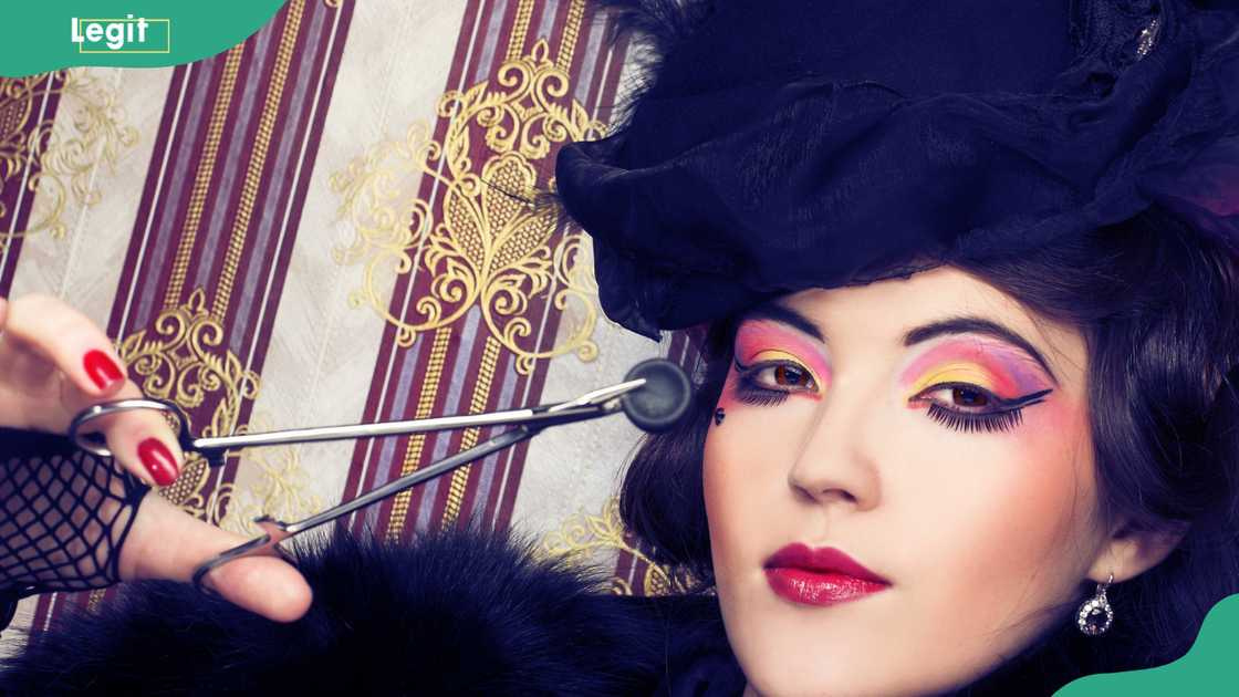 Young lady in vintage hat and with creative visage and forceps